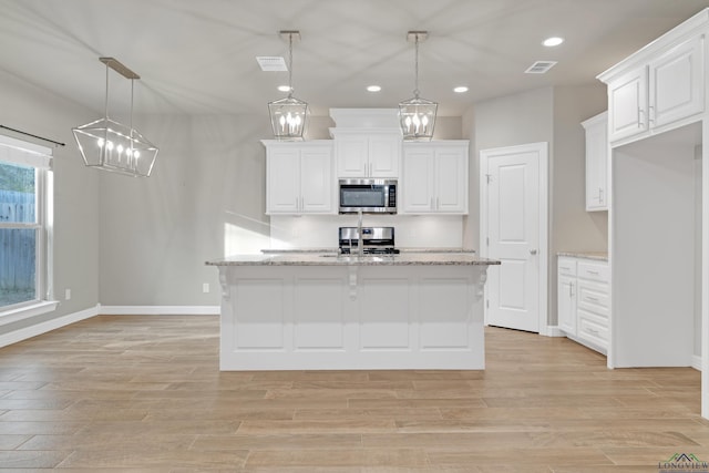 kitchen featuring appliances with stainless steel finishes, pendant lighting, white cabinets, and light stone counters