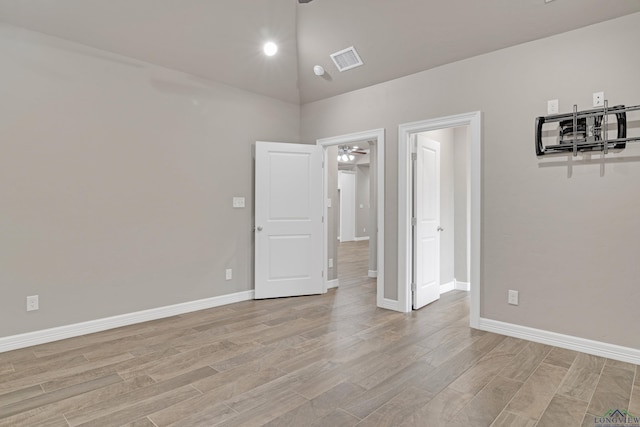 empty room with ceiling fan, high vaulted ceiling, and light hardwood / wood-style floors