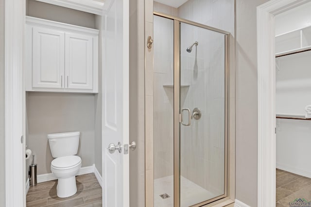 bathroom with a shower with door and toilet