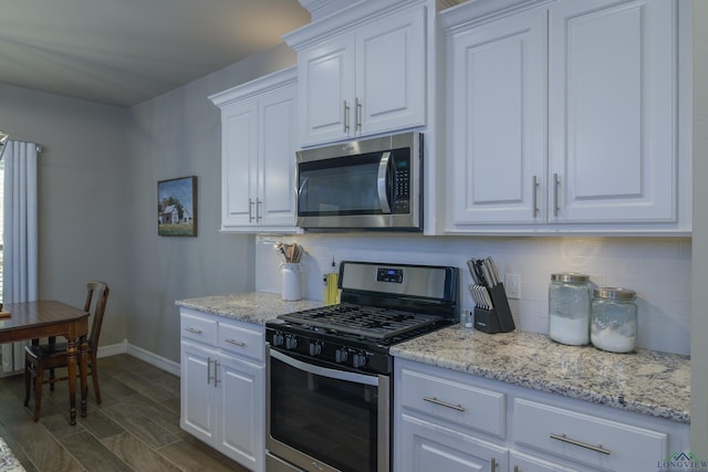 kitchen with tasteful backsplash, appliances with stainless steel finishes, light stone countertops, and white cabinets