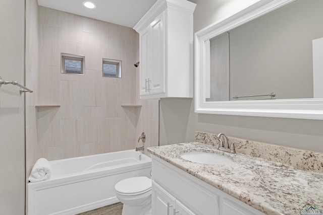 full bathroom featuring vanity, tiled shower / bath combo, and toilet