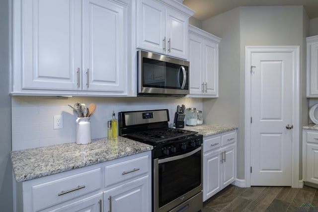 kitchen with white cabinetry, dark hardwood / wood-style flooring, decorative backsplash, stainless steel appliances, and light stone countertops