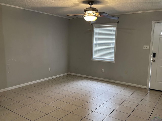 empty room with ceiling fan, light tile patterned flooring, ornamental molding, and a textured ceiling