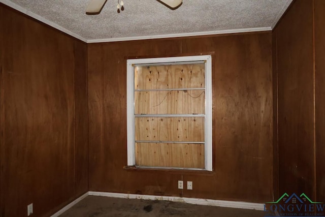 spare room featuring ceiling fan, crown molding, and wooden walls