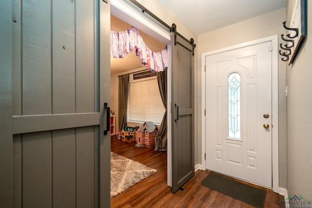 foyer entrance with a barn door and dark wood-type flooring