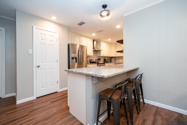 kitchen featuring white cabinetry, stainless steel appliances, wall chimney range hood, kitchen peninsula, and a kitchen bar