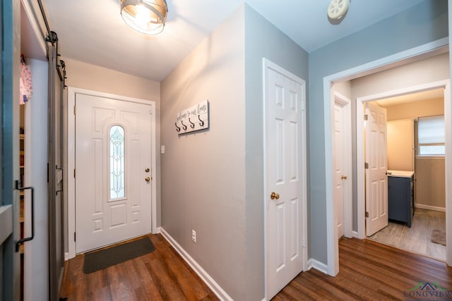 foyer entrance with a barn door and dark wood-type flooring