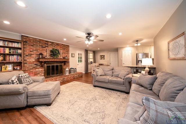 living room featuring a fireplace, wood-type flooring, ceiling fan, and ornamental molding