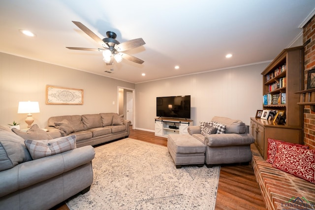 living room with hardwood / wood-style flooring, ceiling fan, ornamental molding, and a brick fireplace