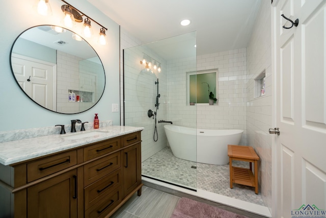 bathroom with shower with separate bathtub and vanity