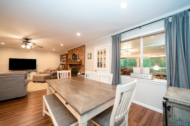 dining space featuring ceiling fan, a fireplace, dark wood-type flooring, and ornamental molding