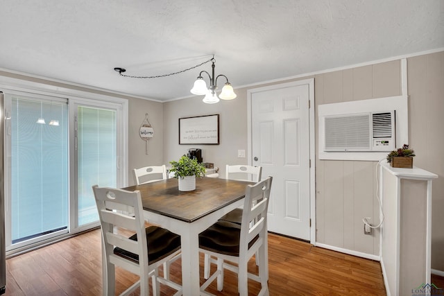 dining area featuring a notable chandelier, an AC wall unit, crown molding, hardwood / wood-style floors, and a textured ceiling