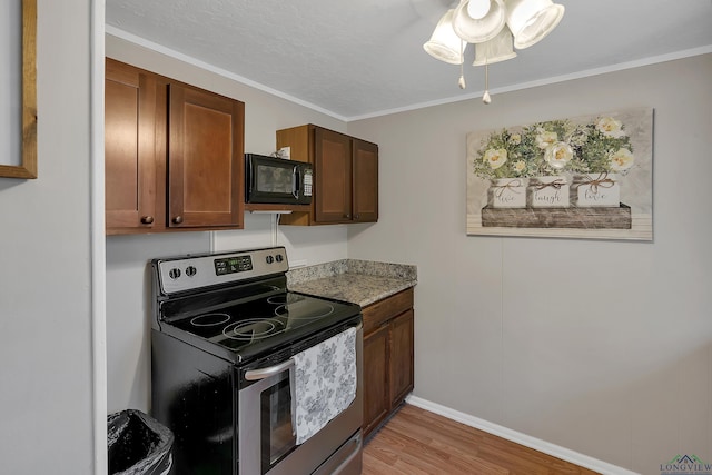 kitchen featuring light stone countertops, black microwave, crown molding, light hardwood / wood-style flooring, and stainless steel electric range