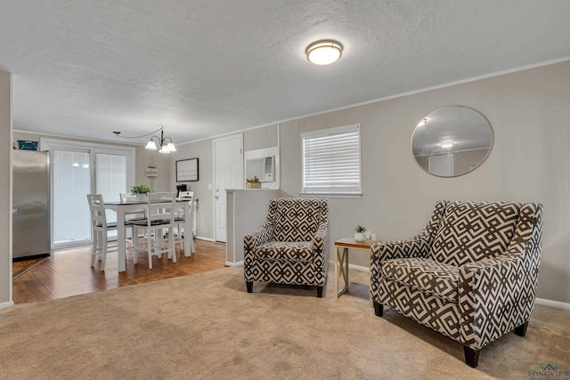 sitting room with carpet flooring, a healthy amount of sunlight, crown molding, and a chandelier