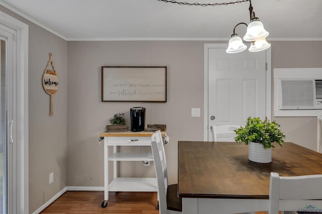 dining area with hardwood / wood-style floors, a notable chandelier, crown molding, and a wall mounted AC