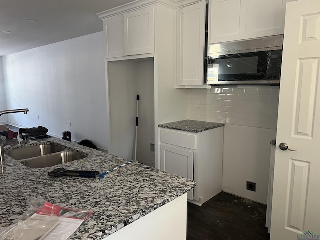 2808 Park Dr, Marshall, TX 75670 - kitchen featuring stainless steel microwave, dark stone countertops, decorative backsplash, dark wood-style floors, and white cabinets