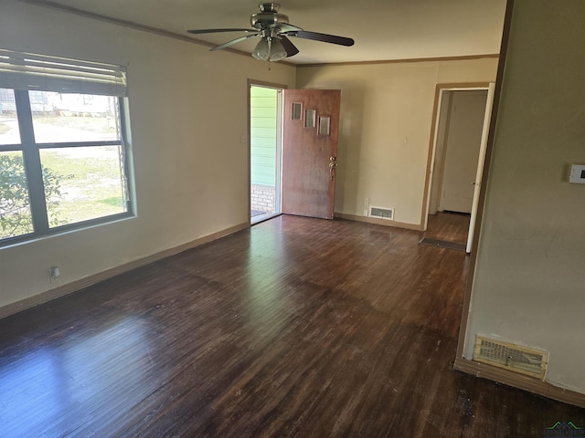 empty room featuring baseboards, visible vents, and dark wood-style flooring