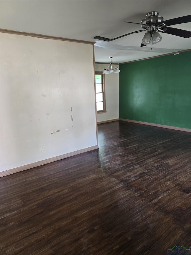 spare room with crown molding, dark wood finished floors, visible vents, ceiling fan, and baseboards