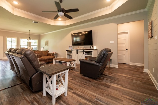 living room featuring ceiling fan with notable chandelier, a raised ceiling, and crown molding