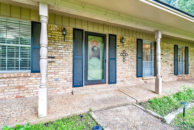 entrance to property with a porch, board and batten siding, and brick siding