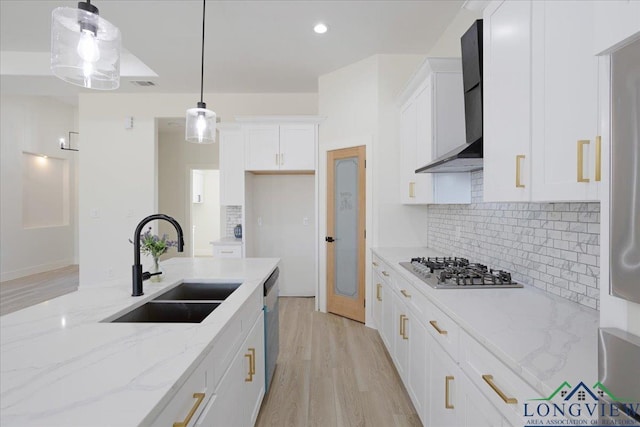 kitchen with pendant lighting, white cabinets, light stone countertops, and wall chimney exhaust hood