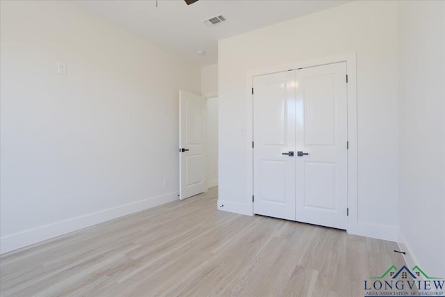 unfurnished bedroom with light wood-type flooring, ceiling fan, and a closet