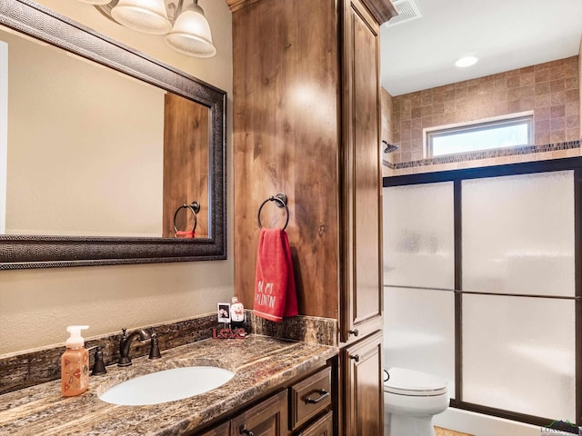 bathroom featuring vanity, toilet, and a shower with shower door