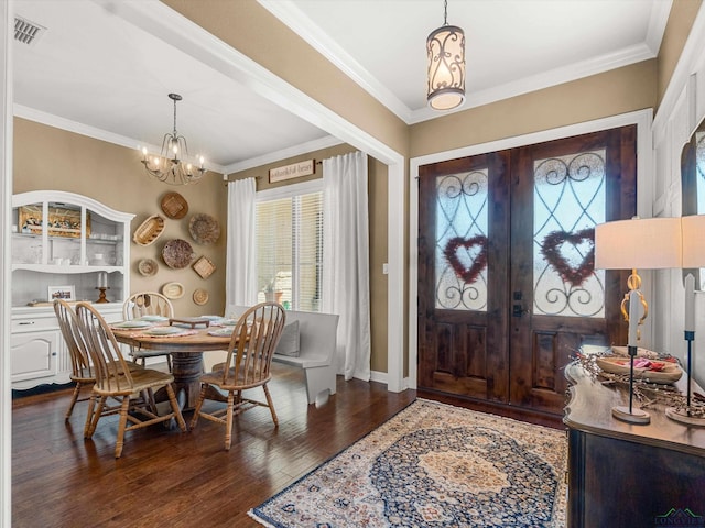 foyer entrance featuring ornamental molding, a healthy amount of sunlight, dark wood-type flooring, and a notable chandelier