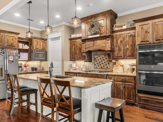 kitchen featuring light stone countertops, stainless steel appliances, an island with sink, and a breakfast bar