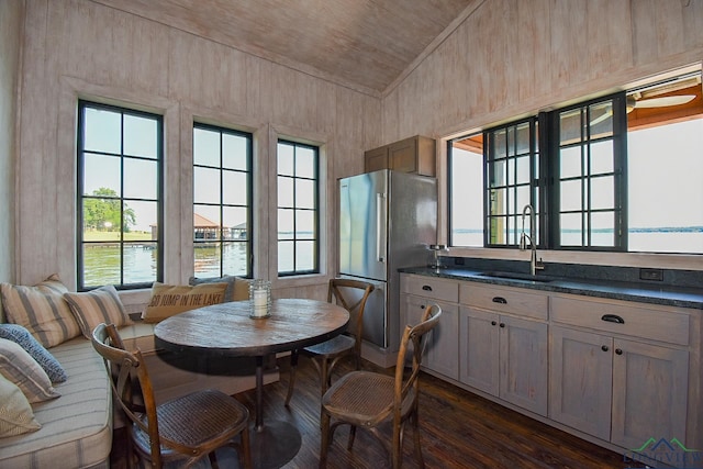 dining area featuring dark hardwood / wood-style flooring, vaulted ceiling, sink, a water view, and wooden ceiling