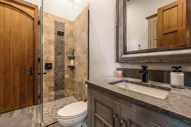 bathroom with a tile shower, vanity, and toilet