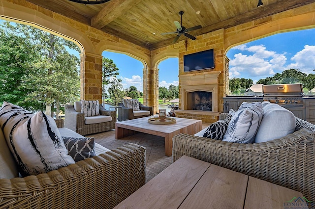 view of patio / terrace with an outdoor stone fireplace, ceiling fan, area for grilling, and an outdoor kitchen