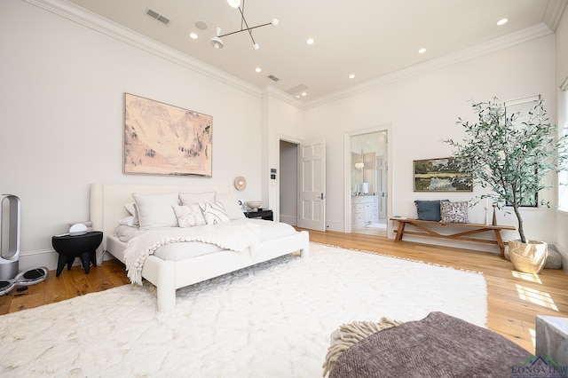 bedroom featuring hardwood / wood-style floors, ensuite bathroom, crown molding, and a notable chandelier