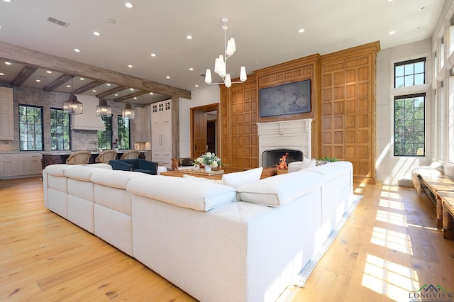 living room featuring beamed ceiling, a notable chandelier, and light wood-type flooring