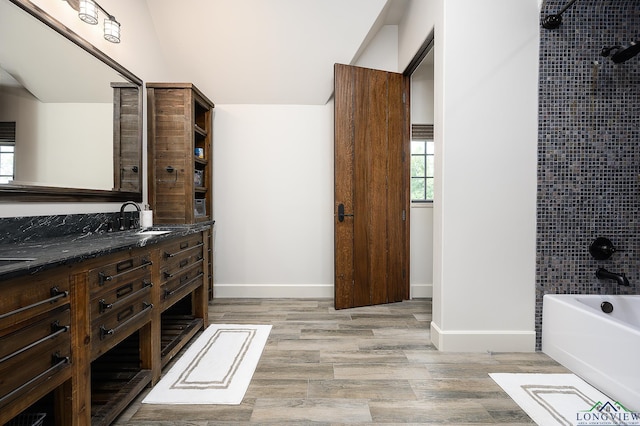 bathroom featuring tiled shower / bath, vanity, lofted ceiling, and hardwood / wood-style flooring