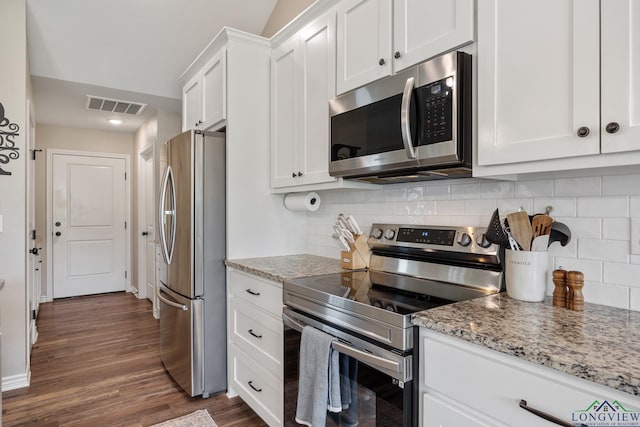 144 Brenlind Ln, Mineola, TX 75773 - kitchen with stainless steel appliances, white cabinets, dark wood finished floors, light stone countertops, and backsplash