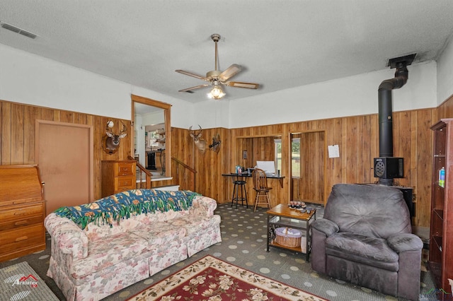 living room featuring wooden walls, ceiling fan, and a textured ceiling