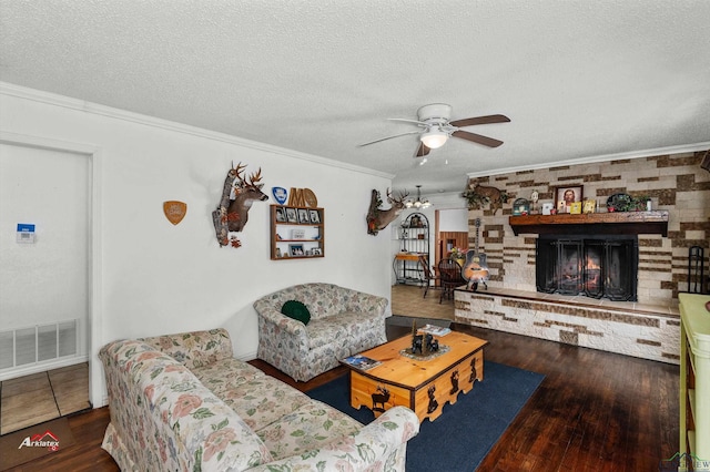 living room with a textured ceiling, a large fireplace, dark hardwood / wood-style floors, and ornamental molding