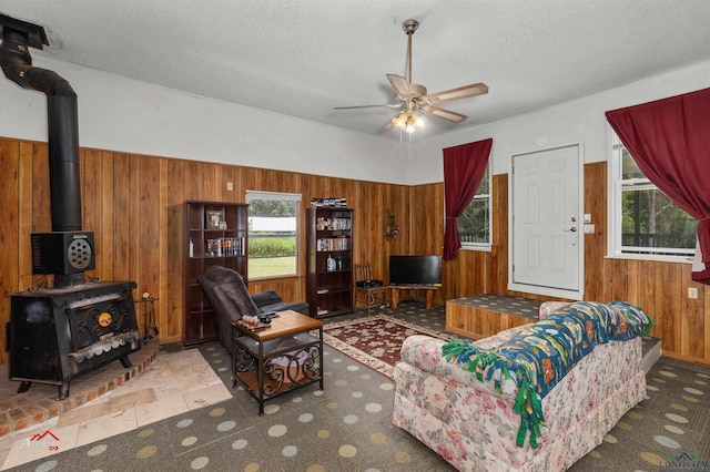 living room with tile patterned flooring, a textured ceiling, ceiling fan, and wood walls