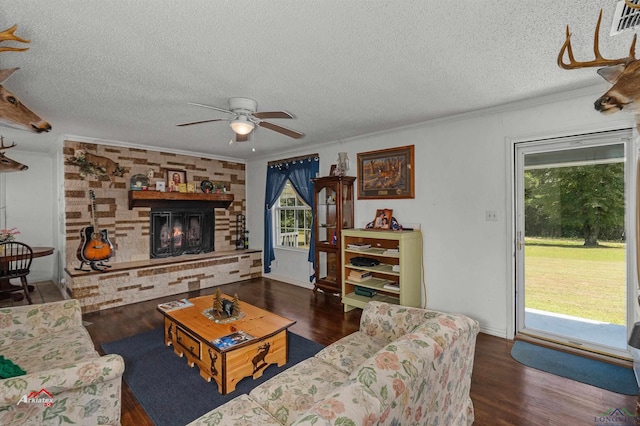 living room with crown molding, ceiling fan, a textured ceiling, a fireplace, and dark hardwood / wood-style flooring