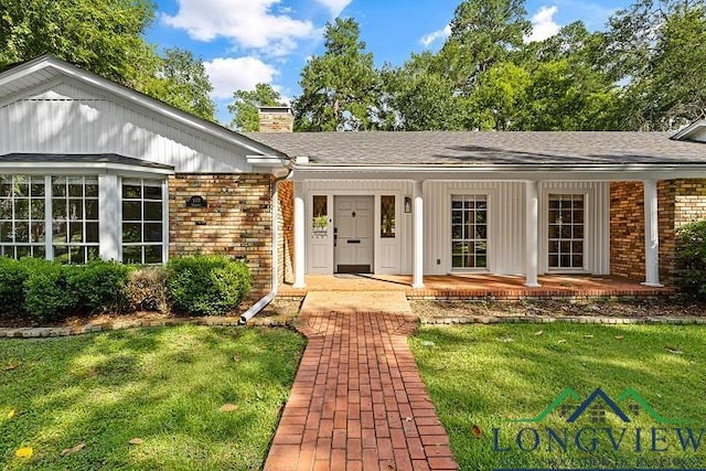 view of exterior entry featuring a yard and a porch