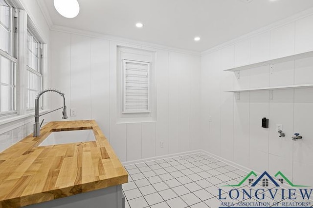 laundry area with tile patterned floors, sink, and ornamental molding