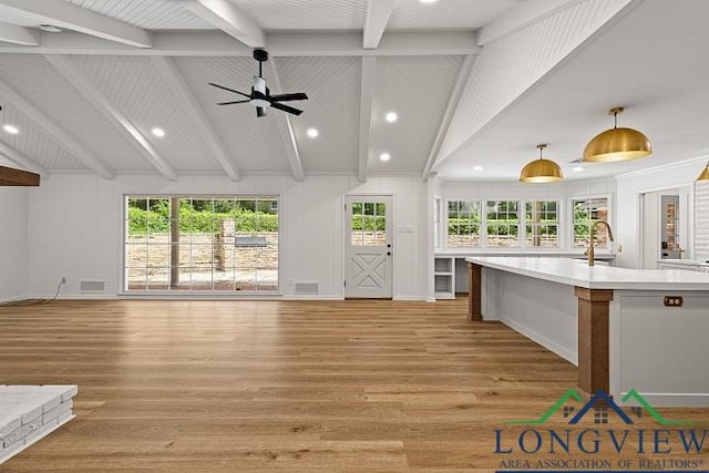 unfurnished living room featuring vaulted ceiling with beams, light hardwood / wood-style flooring, ceiling fan, and sink