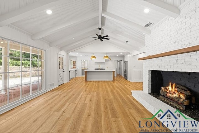 unfurnished living room featuring vaulted ceiling with beams, ceiling fan, a fireplace, and light hardwood / wood-style flooring