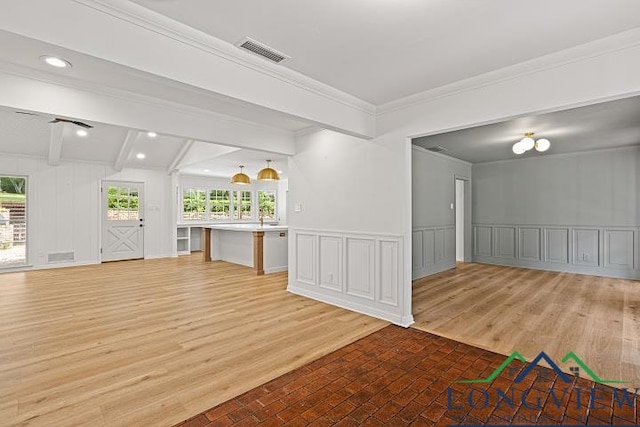 unfurnished living room featuring beamed ceiling, light hardwood / wood-style flooring, and crown molding