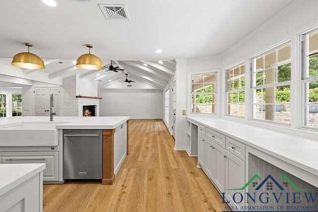 kitchen with ceiling fan, vaulted ceiling with beams, stainless steel dishwasher, decorative light fixtures, and white cabinets