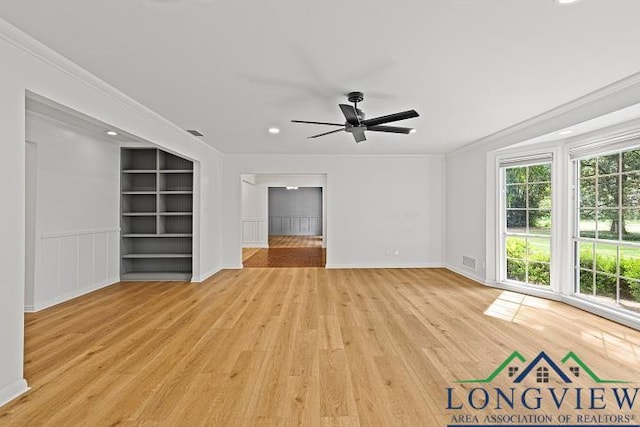 unfurnished living room with built in shelves, light hardwood / wood-style floors, ceiling fan, and ornamental molding