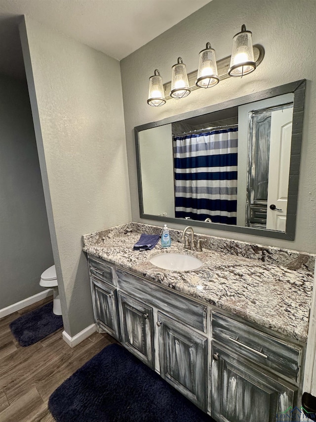 bathroom featuring hardwood / wood-style flooring, vanity, curtained shower, and toilet