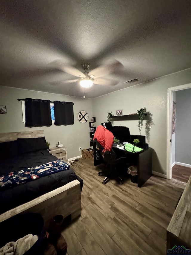 bedroom with ceiling fan, hardwood / wood-style floors, and a textured ceiling