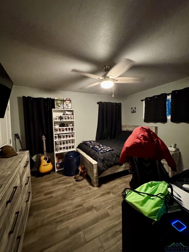 bedroom featuring ceiling fan, dark hardwood / wood-style flooring, and a textured ceiling